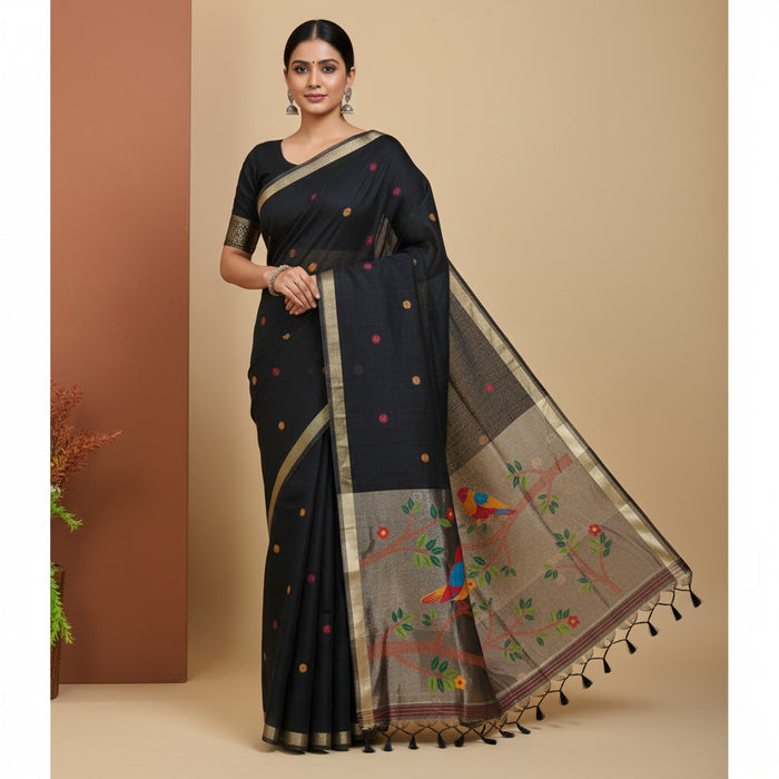 Black saree with colorful patterns draped over a chair next to a floral arrangement.